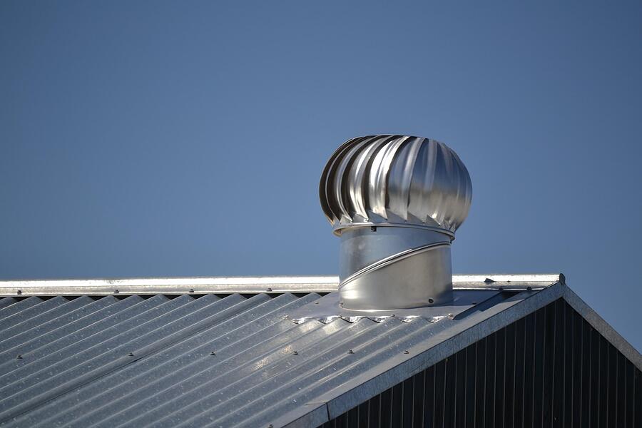 A turbine vent on a metal roof, the kind of vent base that cracks in the Houston sun