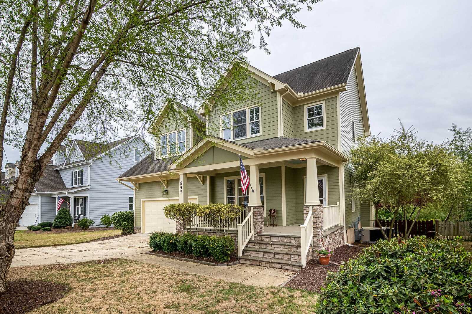 A two-story suburban house with a shade tree in the front yard